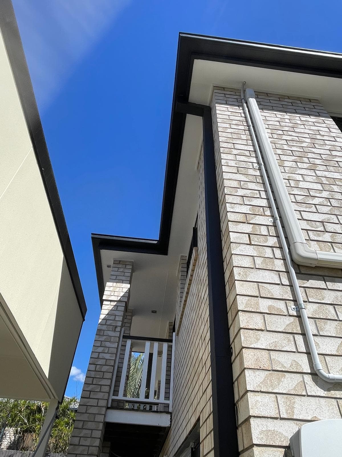 Brick home balcony with white railing and dark fascia