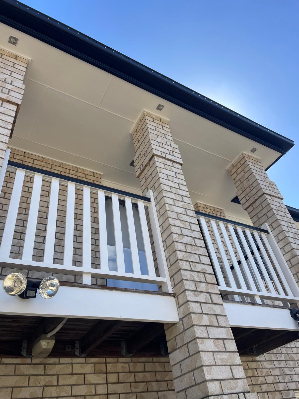 Balcony soffit, white railings and brick columns from below