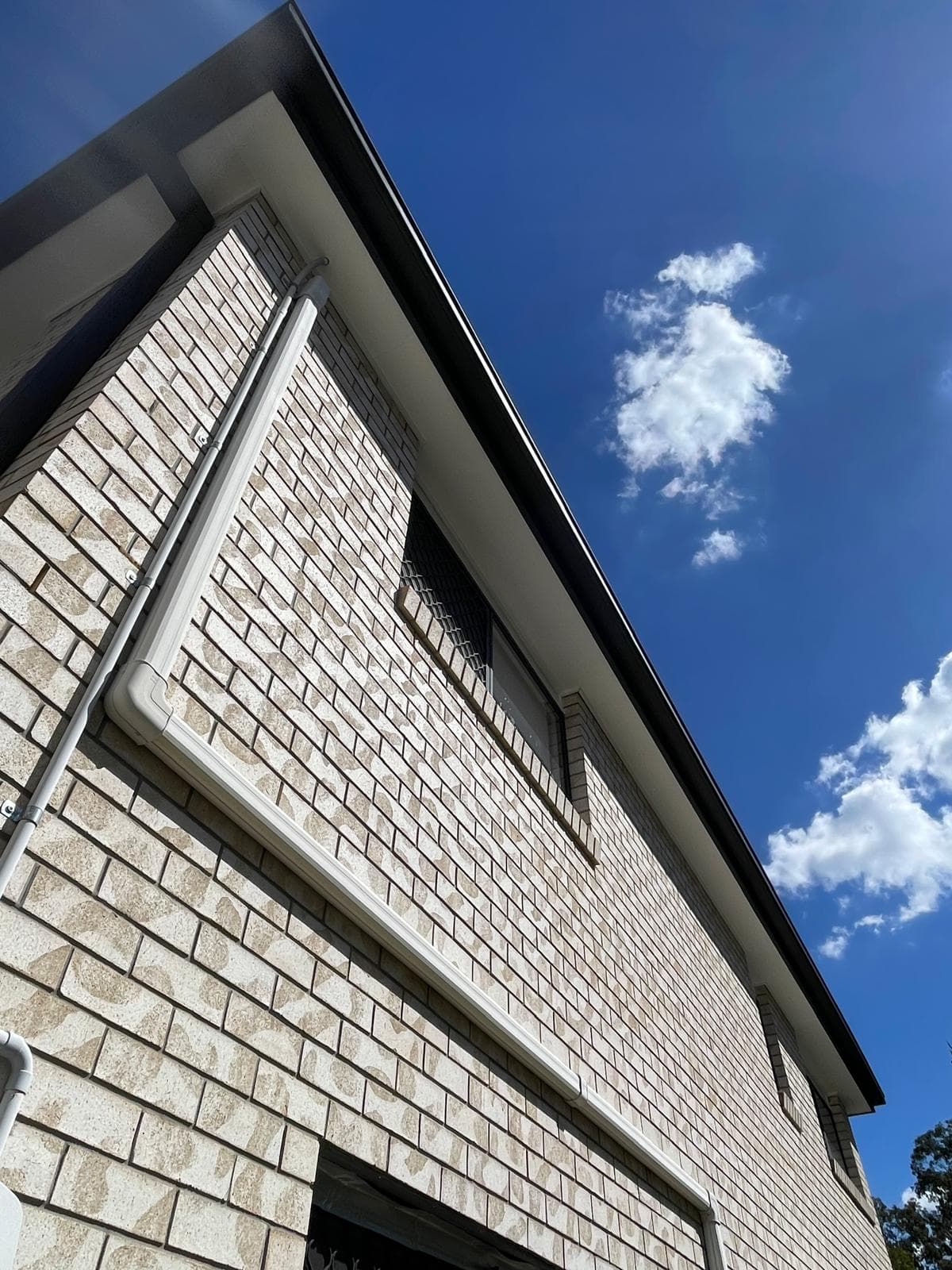 Cream brick two-storey home against bright blue sky