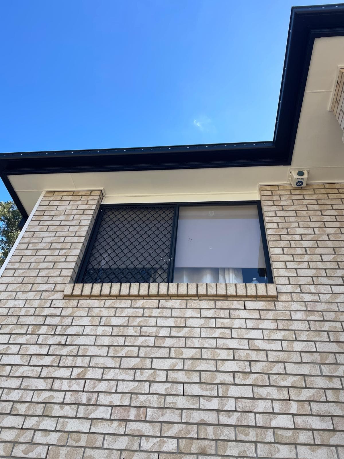 Cream brick wall with black-framed window and clean white eaves