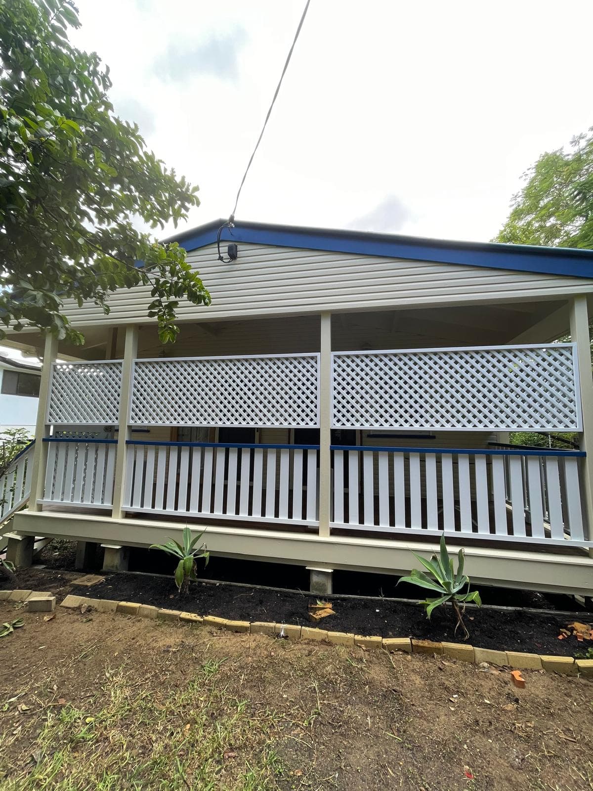 Cream weatherboard porch with navy fascia and white lattice